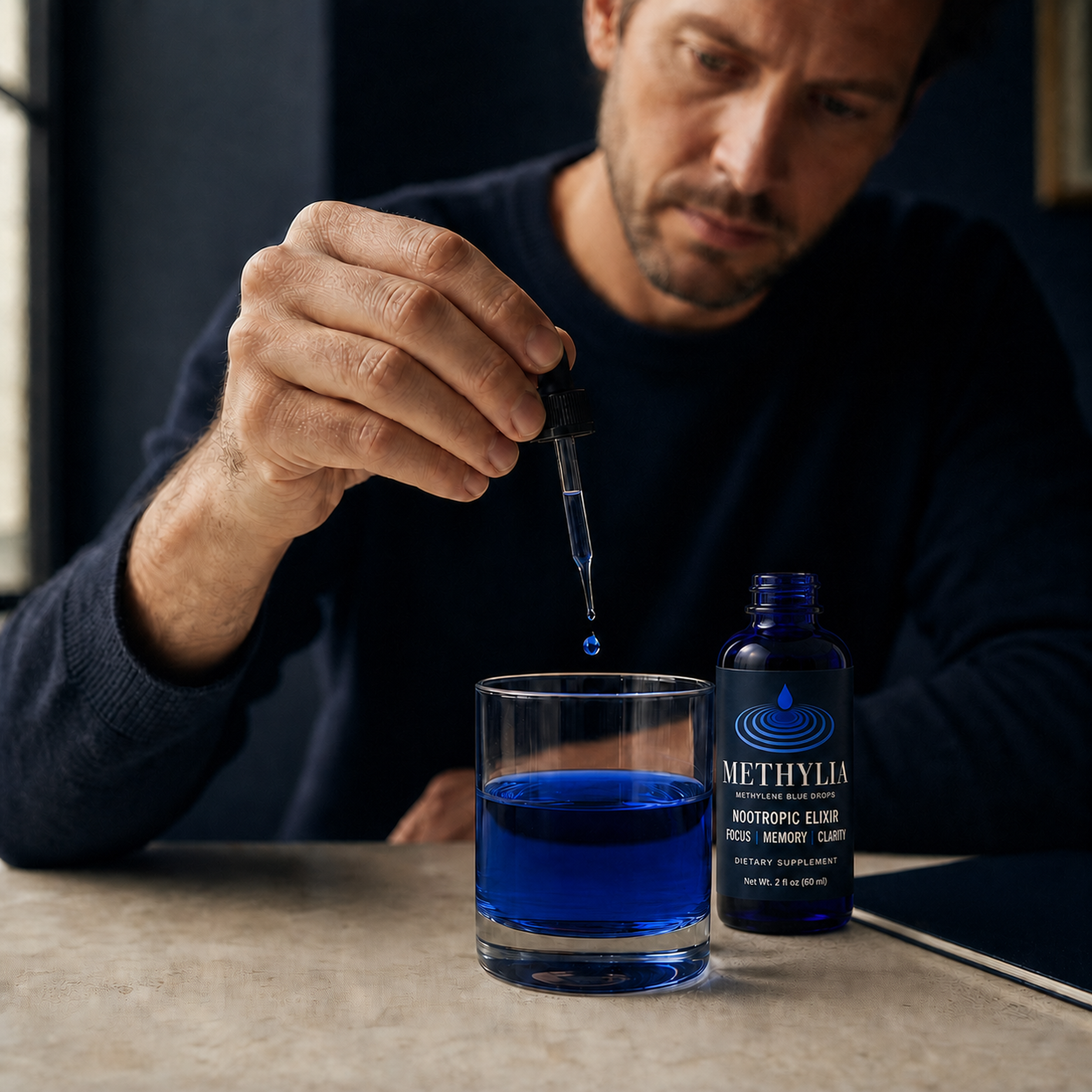 A person adding Methylia drops to a glass of blue water with the open bottle beside it